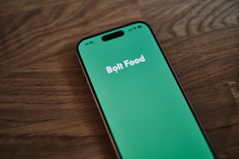 Smartphone displaying a food-delivery app on a wooden table