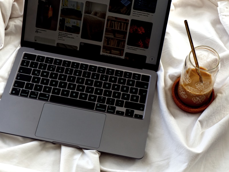 Laptop and morning coffee on a white sheet, scrolling a content feed