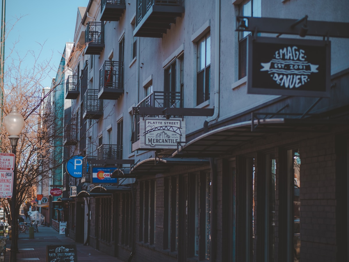 Row of small-business storefronts on a city street with mercantile signage